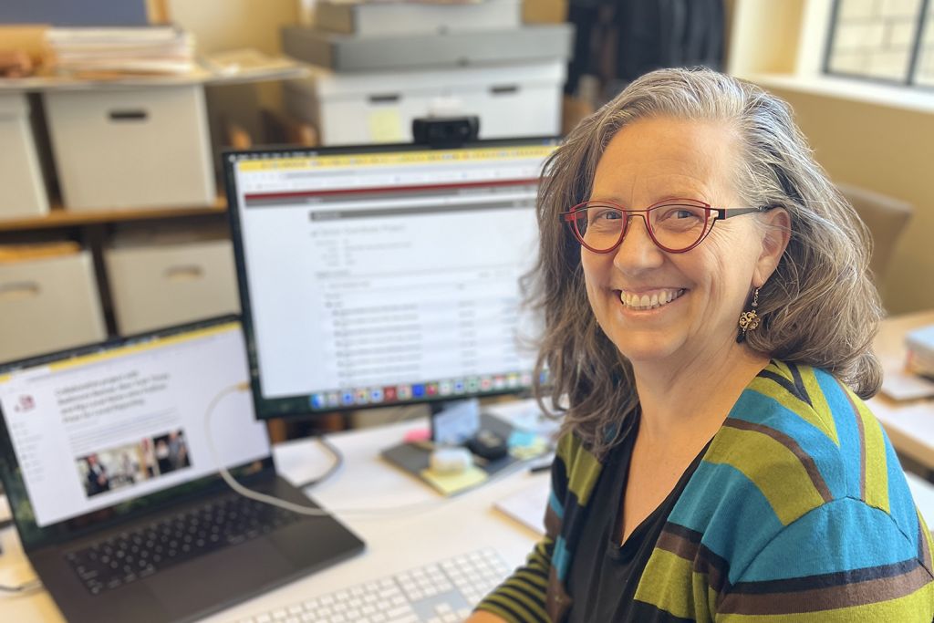 Photo of Regina Roberts sitting at her desk in her office and smiling for the photo.
