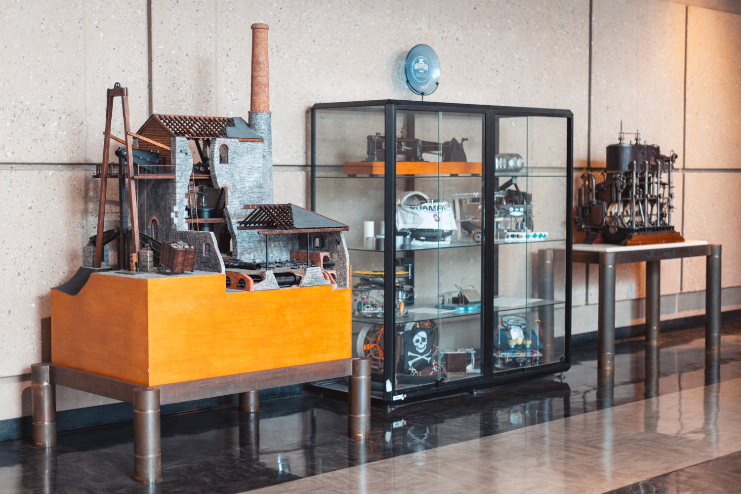 Two industrial models in a hallway on either side of a display case