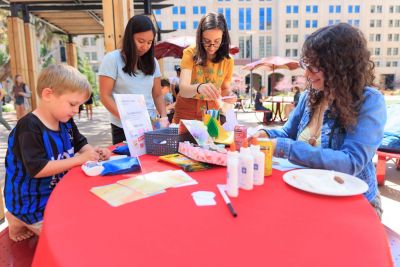 Students and their children at a table with craft supplies.