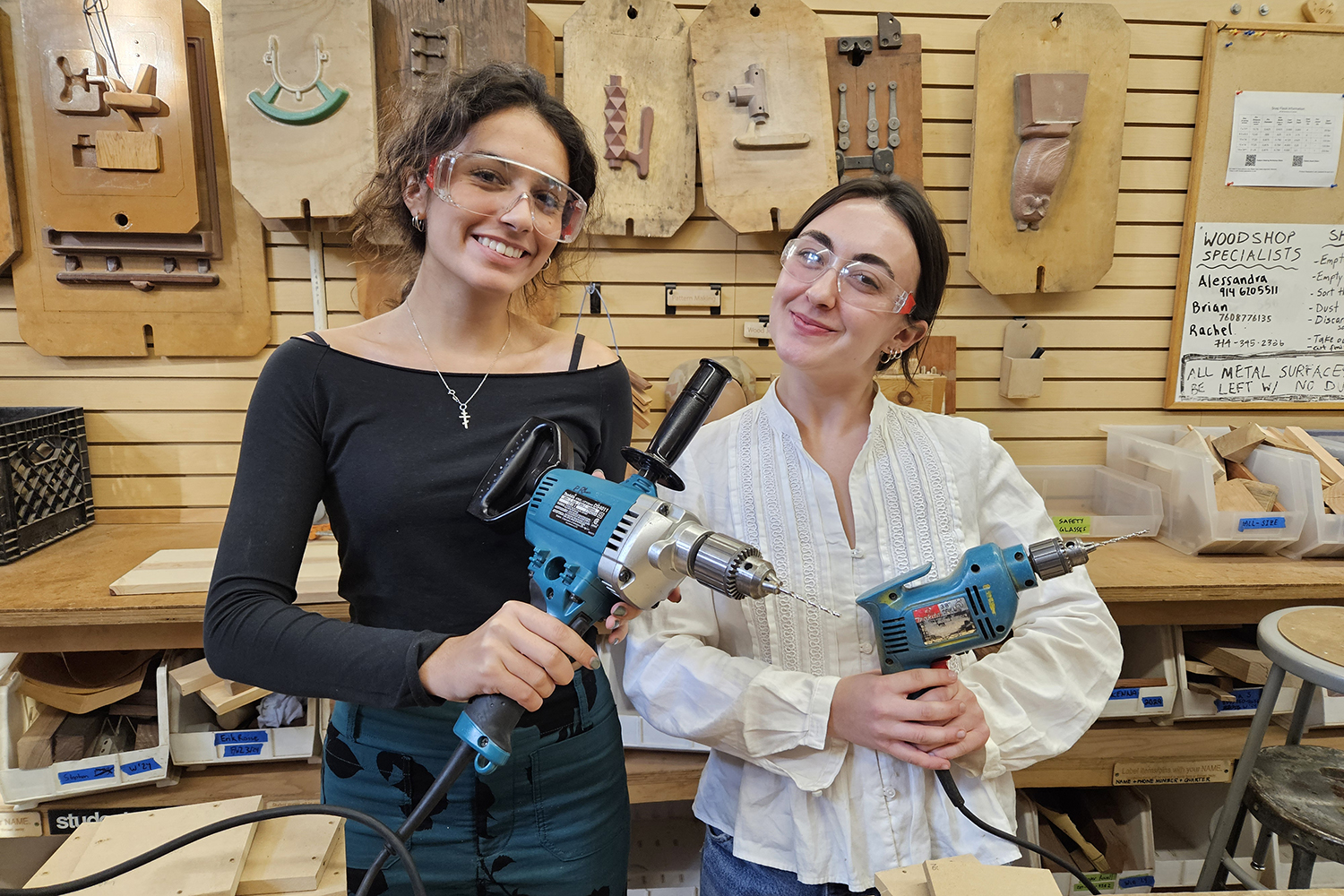 Students in a woodshop workshop pose for a photo with their tools. (opens in a modal)