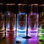 bottles glow in rainbow colors as laser causes nanoparticles suspended in cyclohexane to emit light
