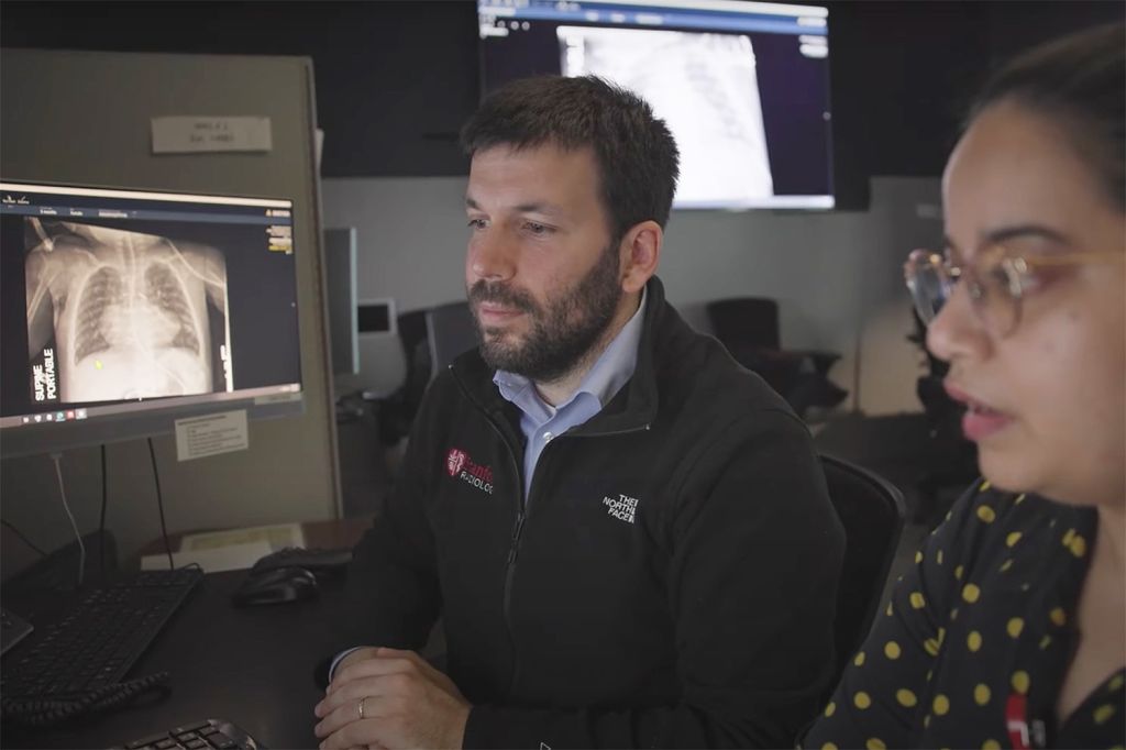 Image of Akshay Chaudhari and another researchers looking at data of chest X-rays on a computer screen.