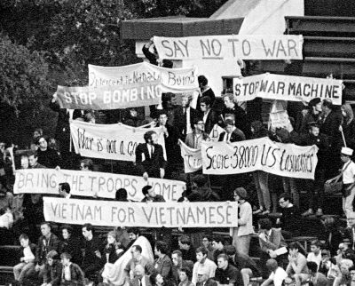 Students holding protest signs at a football game