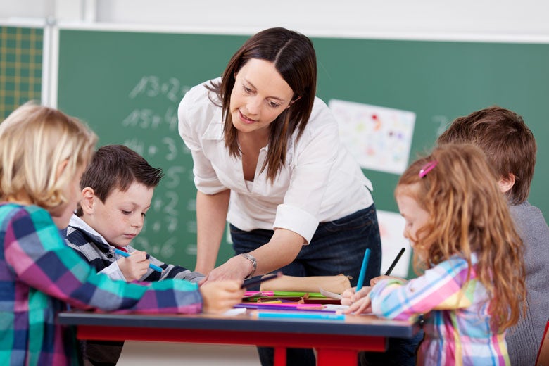 teacher assisting elementary grade students / racorn/Shutterstock