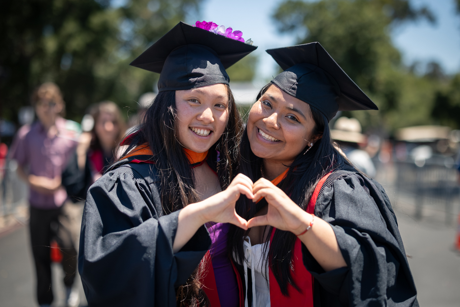 Two grads make a heart sign
