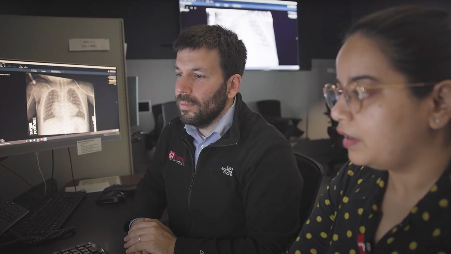Image of Akshay Chaudhari and another researchers looking at data of chest X-rays on a computer screen.