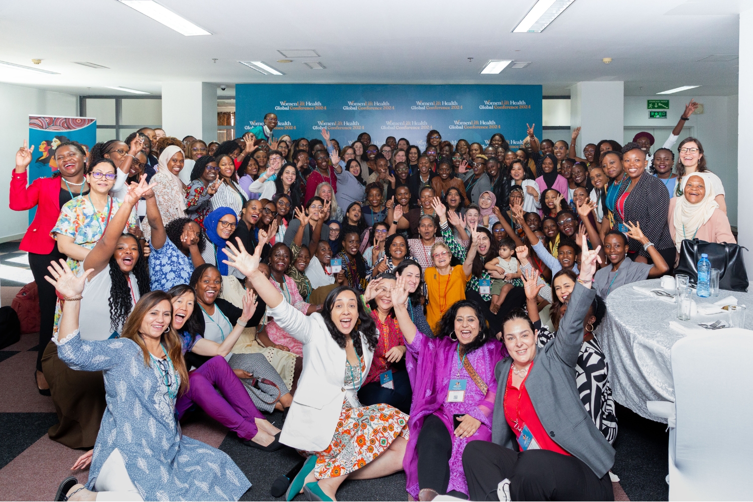 A diverse group of women enthusiastically poses together at the Women’s Global Health Conference, showcasing camaraderie and celebration.