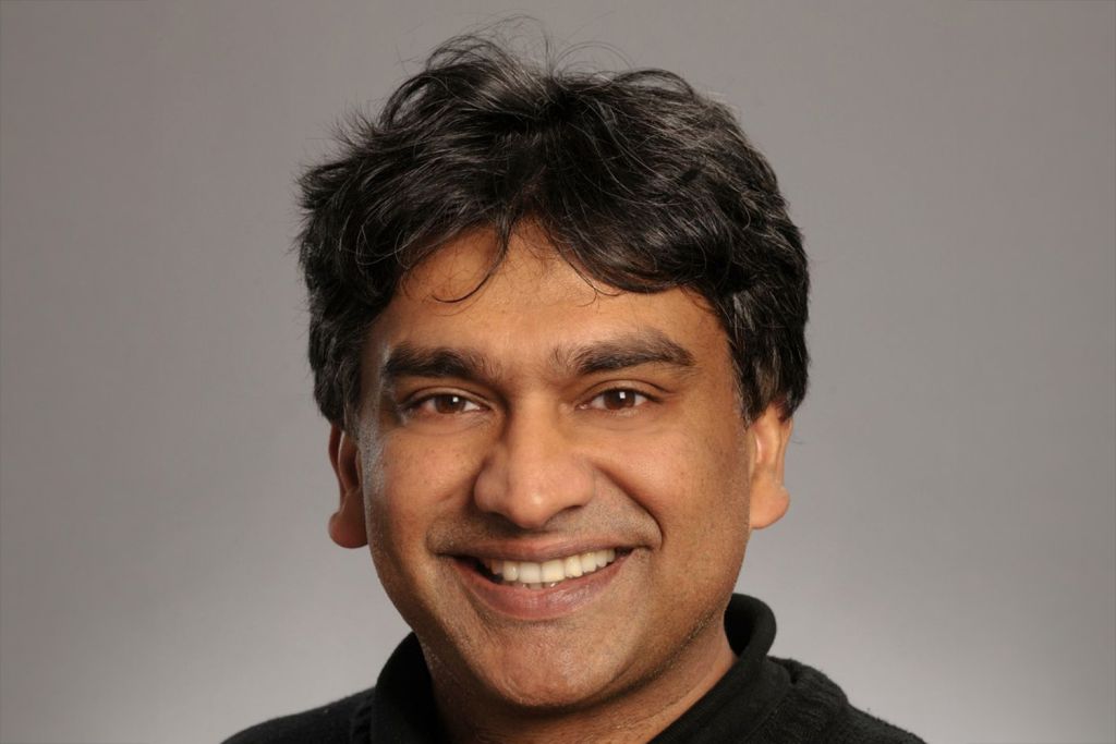 Bali Pulendran smiling into the camera against a gradient gray background.