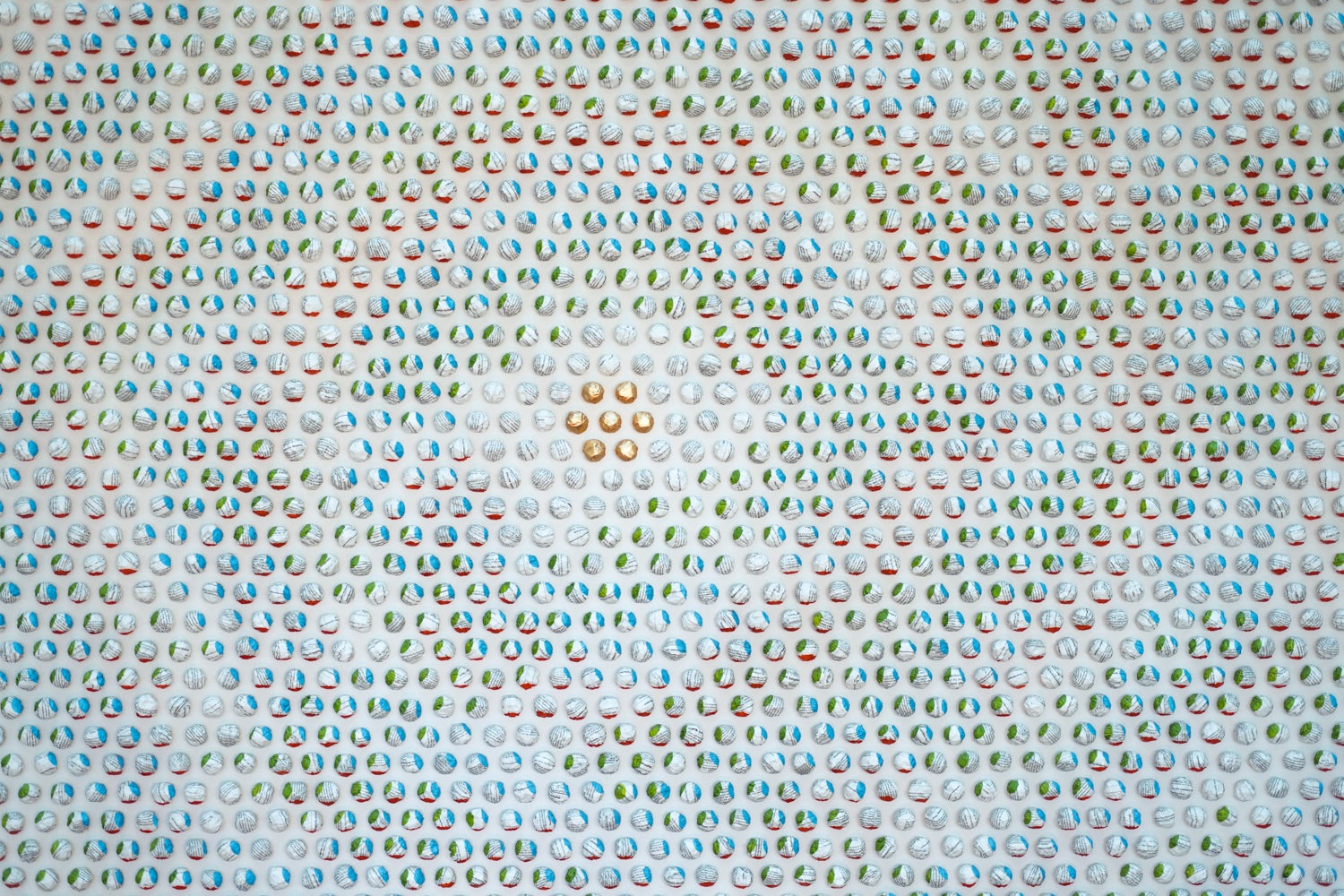 Close-up of art made of balled up paper, dipped in paint that creates different patterns from different angles. There are 7 gold balls in the middle.