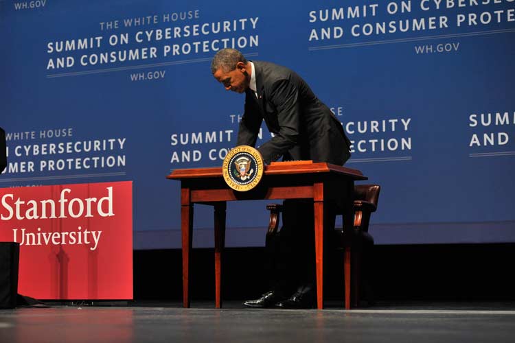 President Obama behind a table on stage signing an executive order