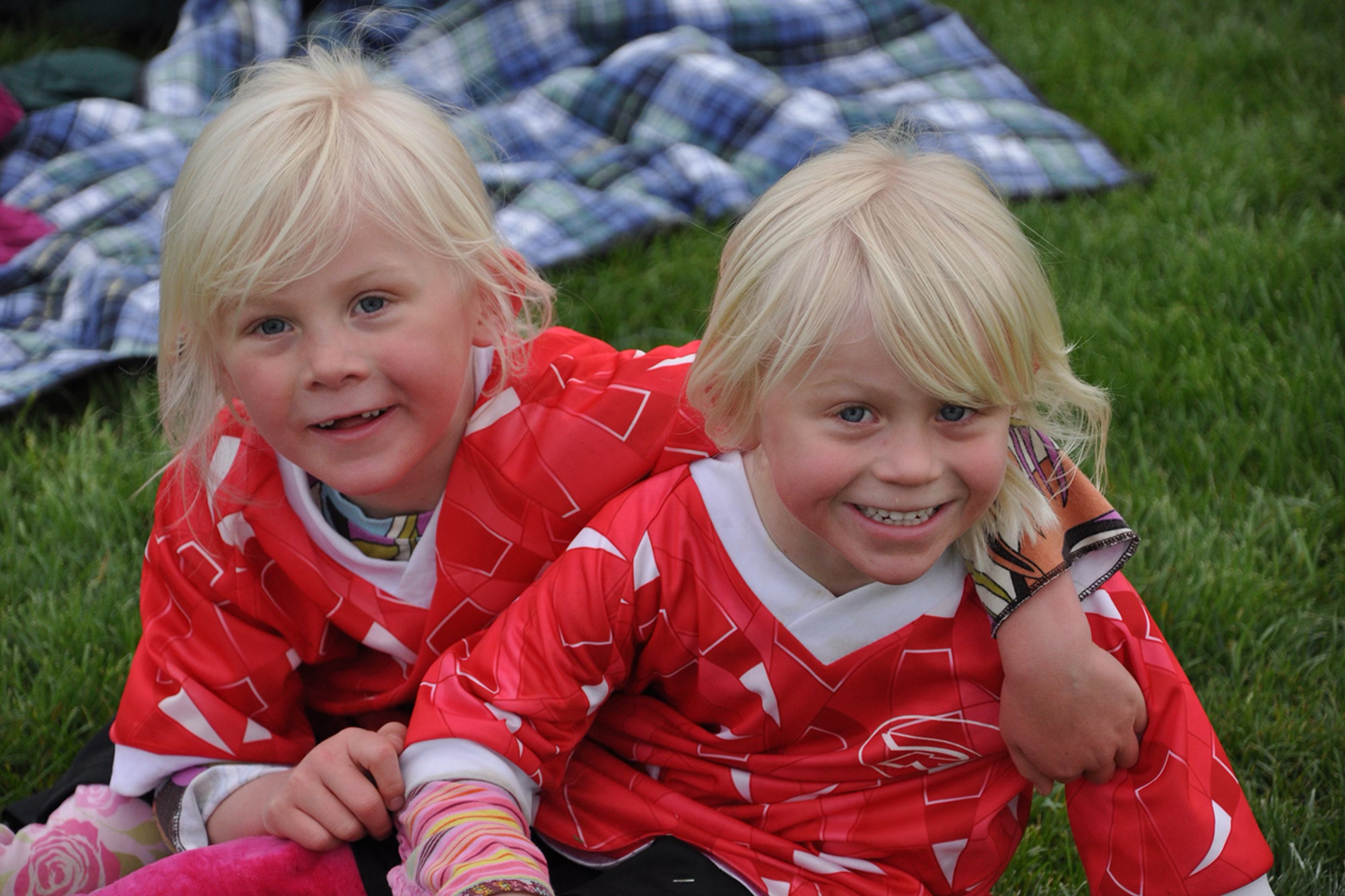 Logan and Sammy Smith wearing jerseys and sitting on the grass while posing for a photo.