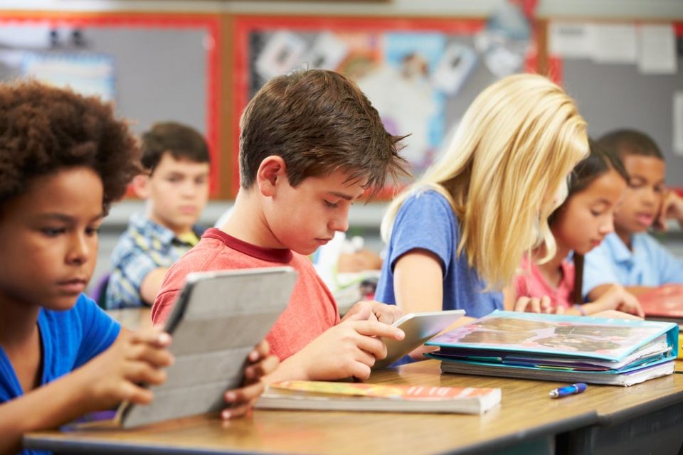 elementary school students reading at classroom desks