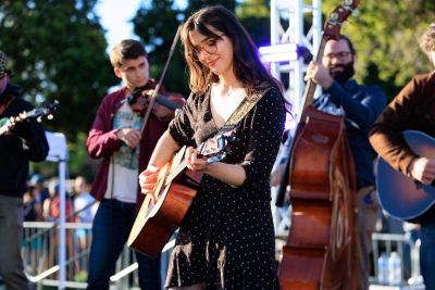 Student playing a guitar on stage.