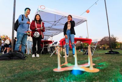 Three students playing a lawn game.