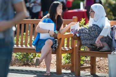 two prospective students chatting on bench