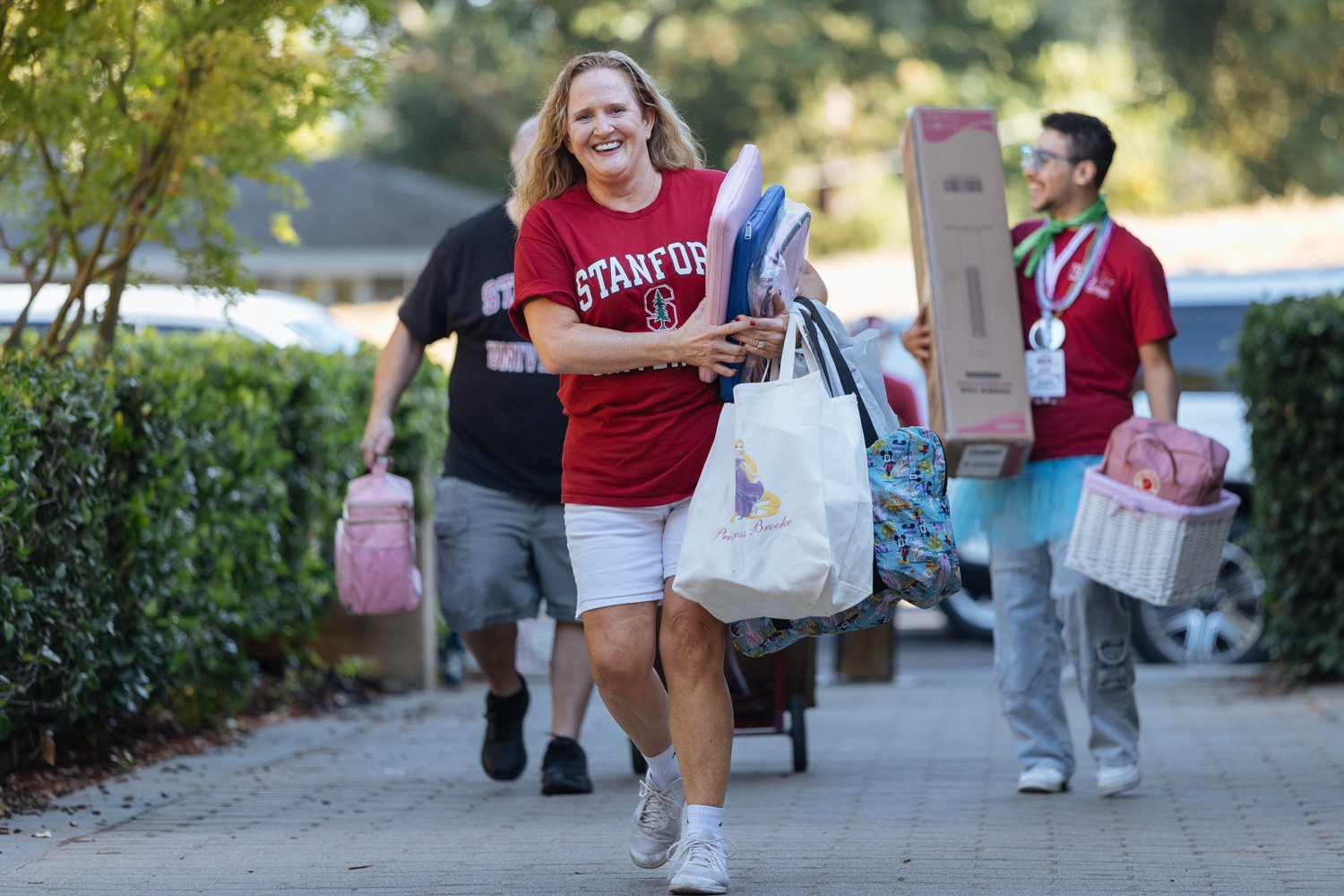 People carrying bags of belongings as students move in.