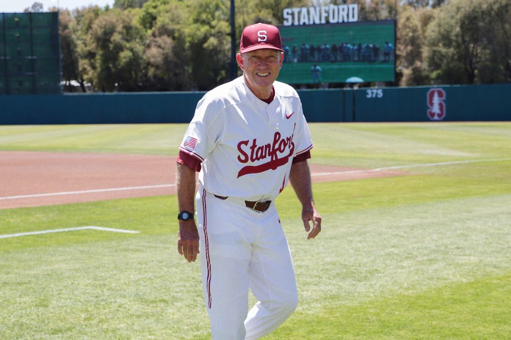 Baseball head coach Mark Marquess wearing a Cardinal uniform and walking across the field.