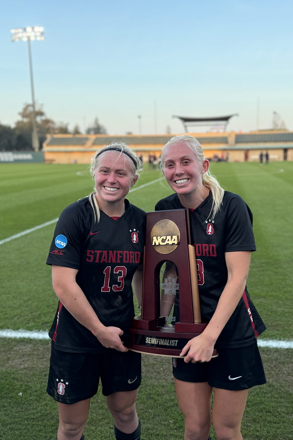 Logan and Sammy Smith posing for a photo with an NCAA soccer trophy.