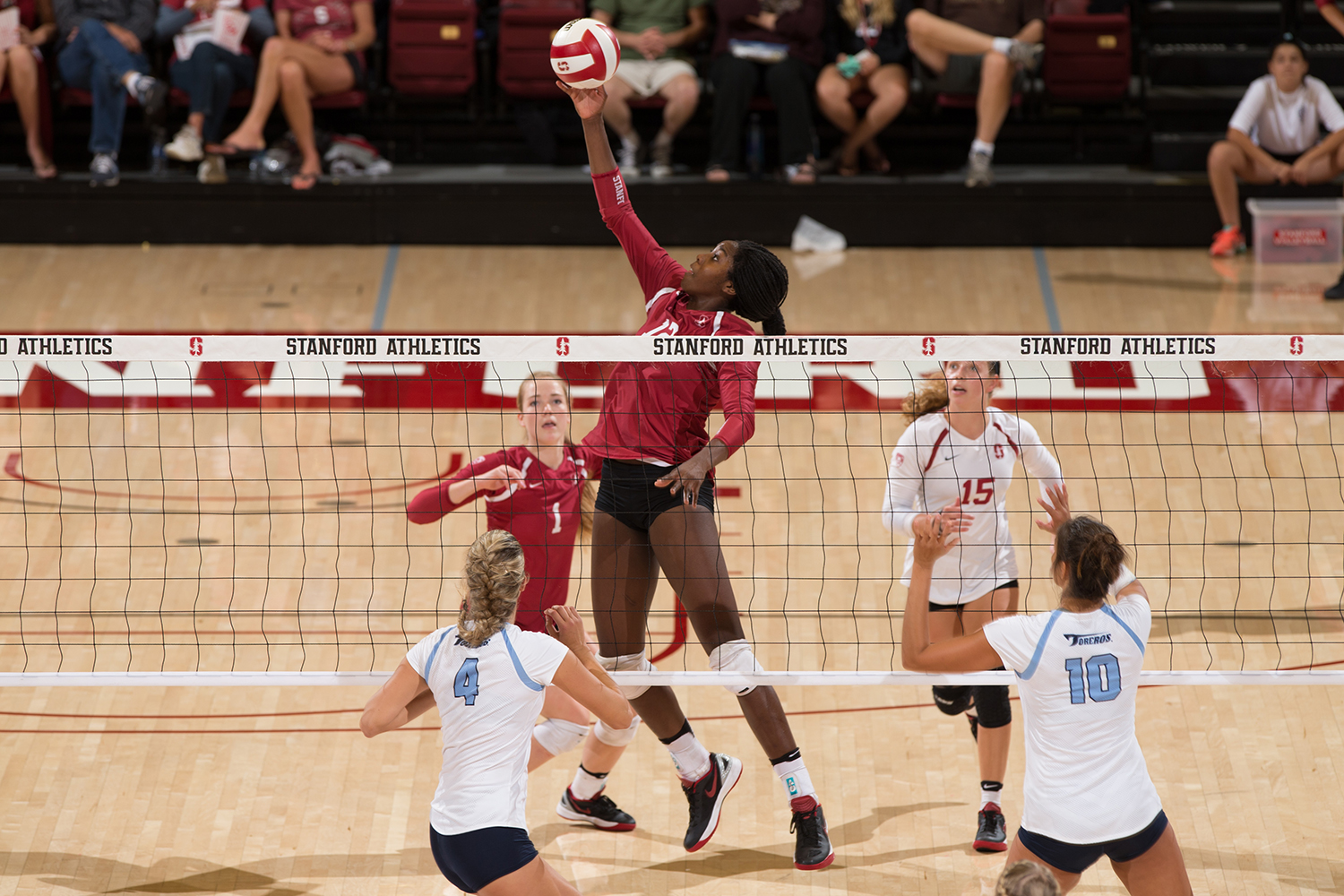 Stanford volleyball player Inky Ajanaku leaps above the net to spike the ball during a match against University of San Diego Toreros.