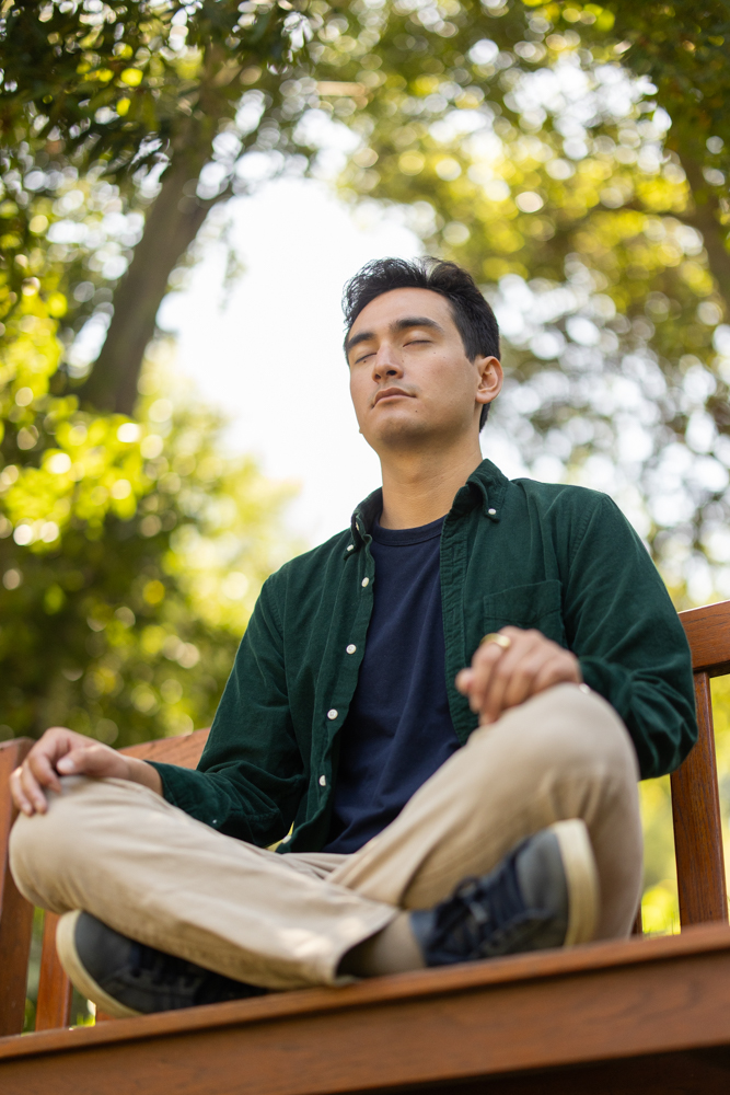 Pictured is Zaidel meditating cross-legged on a bench on the Stanford campus.