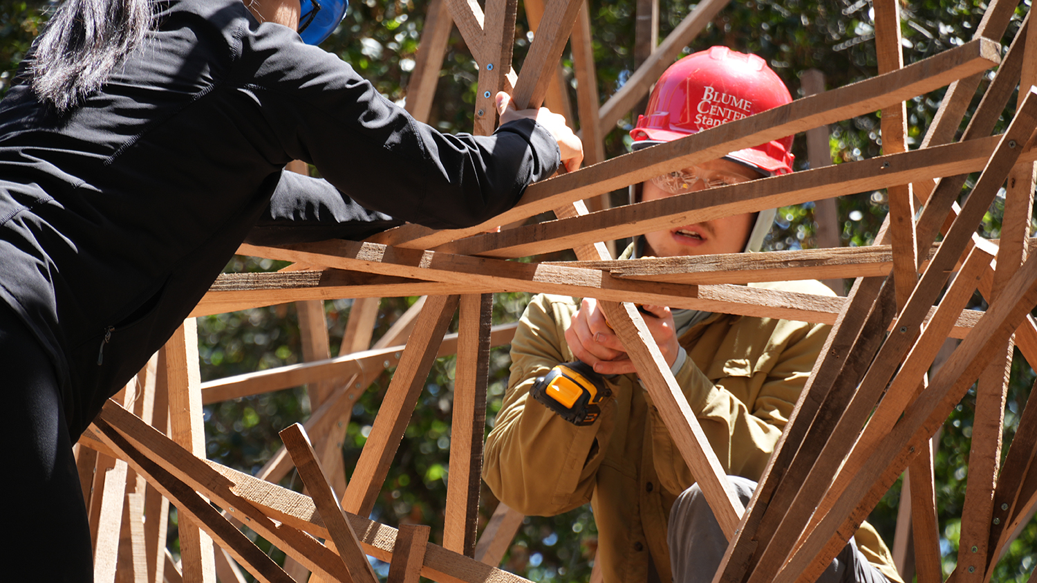 People working on construction, with closeup of one in hardhad, goggles, and tools