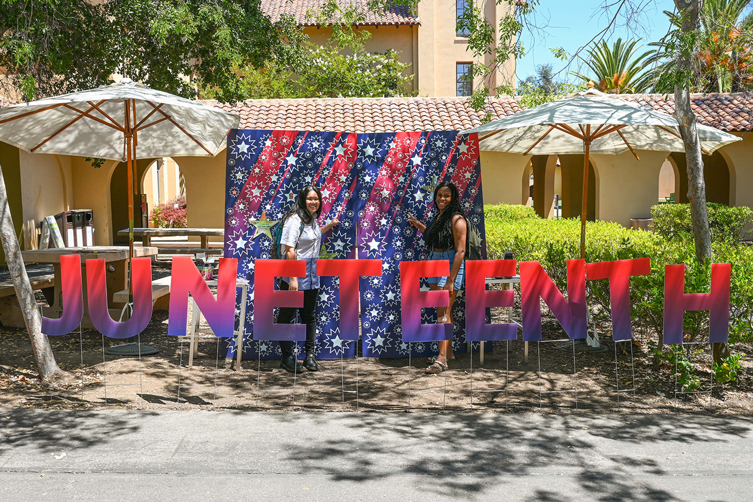 Pictured are two students standing behind a large Juneteenth sign.  