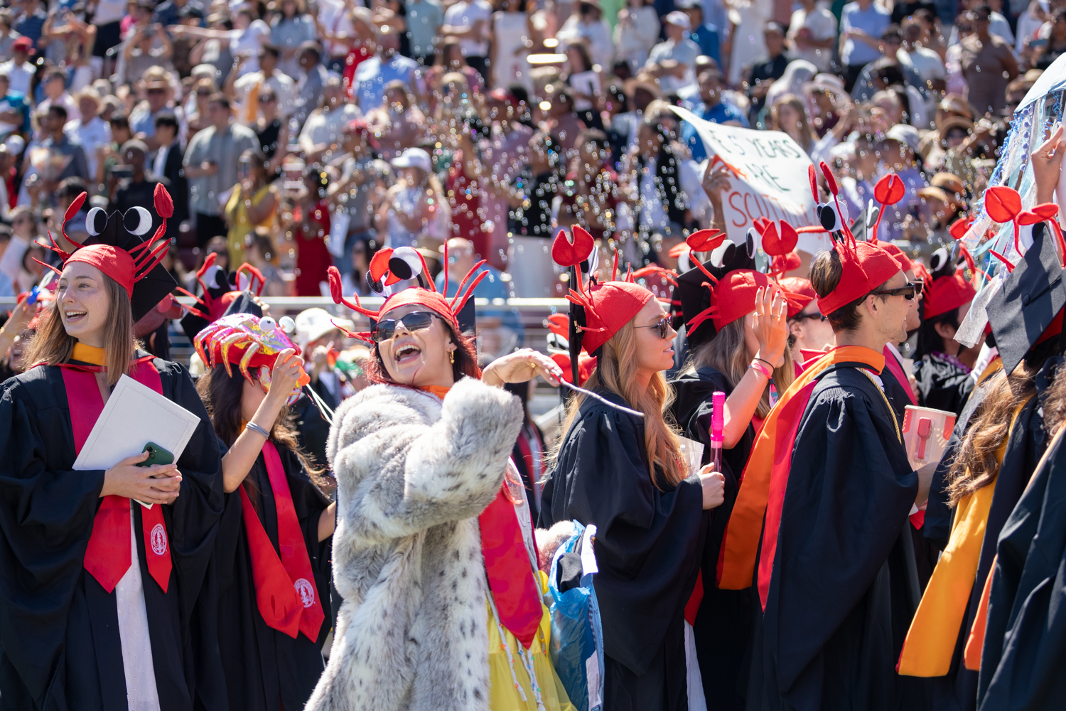 Photo depicts students from the graduating Class of 2024 wearing crab shaped hats during the Wacky Walk parade into the stadium.