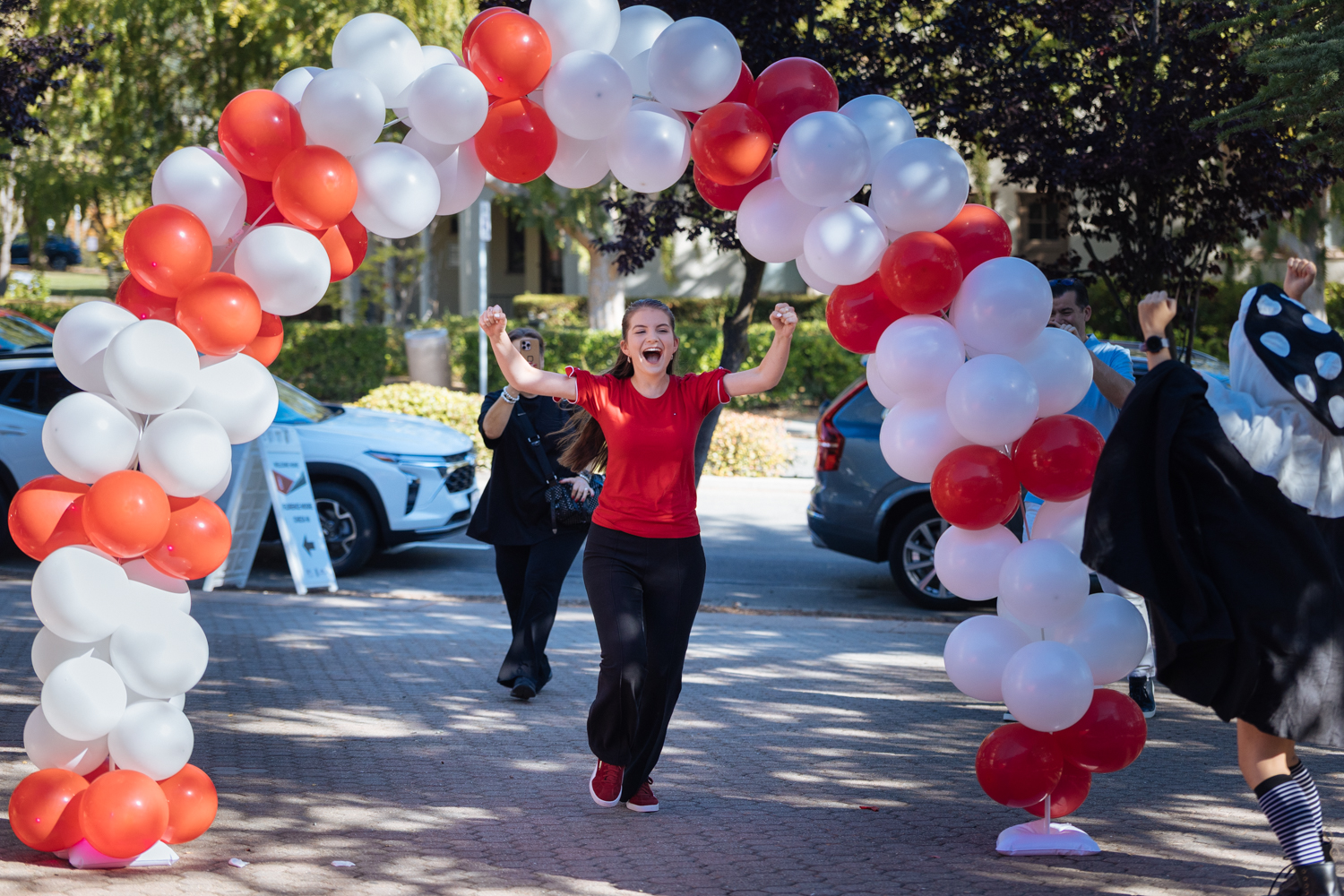 Student runs through balloon arch outside FloMo.