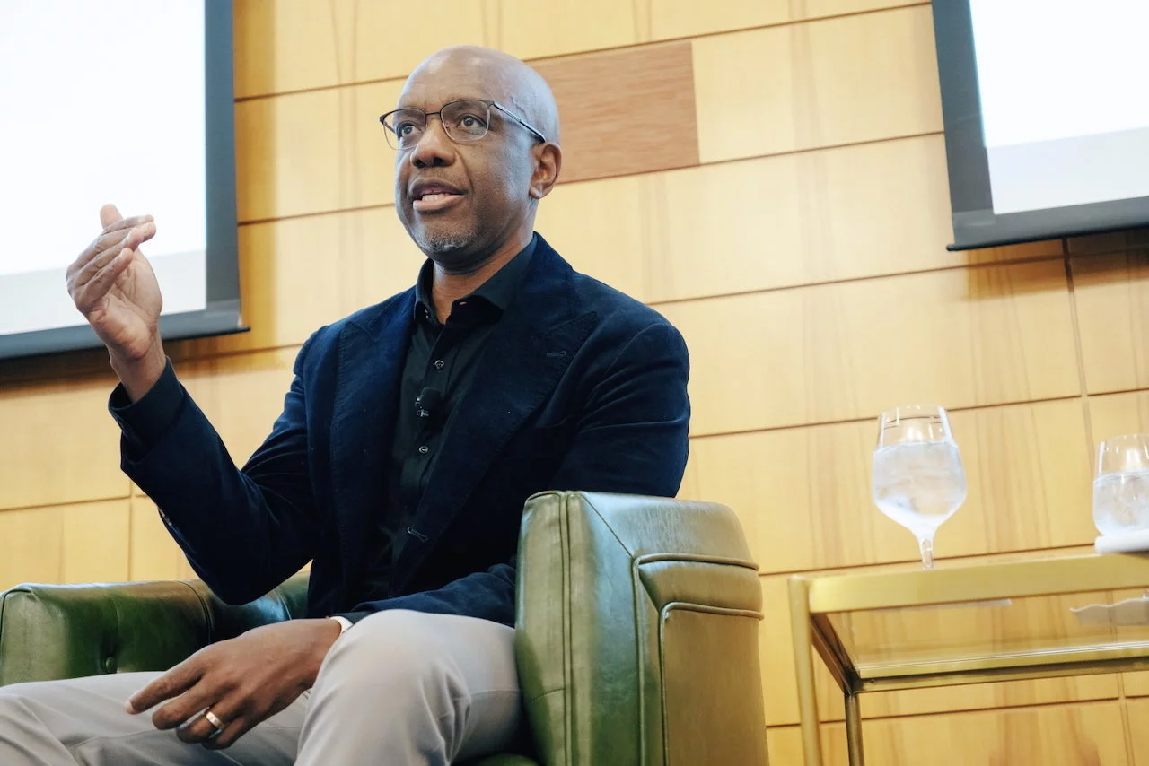 James Manyika, senior vice president at Google, seated in a club chair and gesturing as he speaks onstage at the SIEPR Policy Forum.
