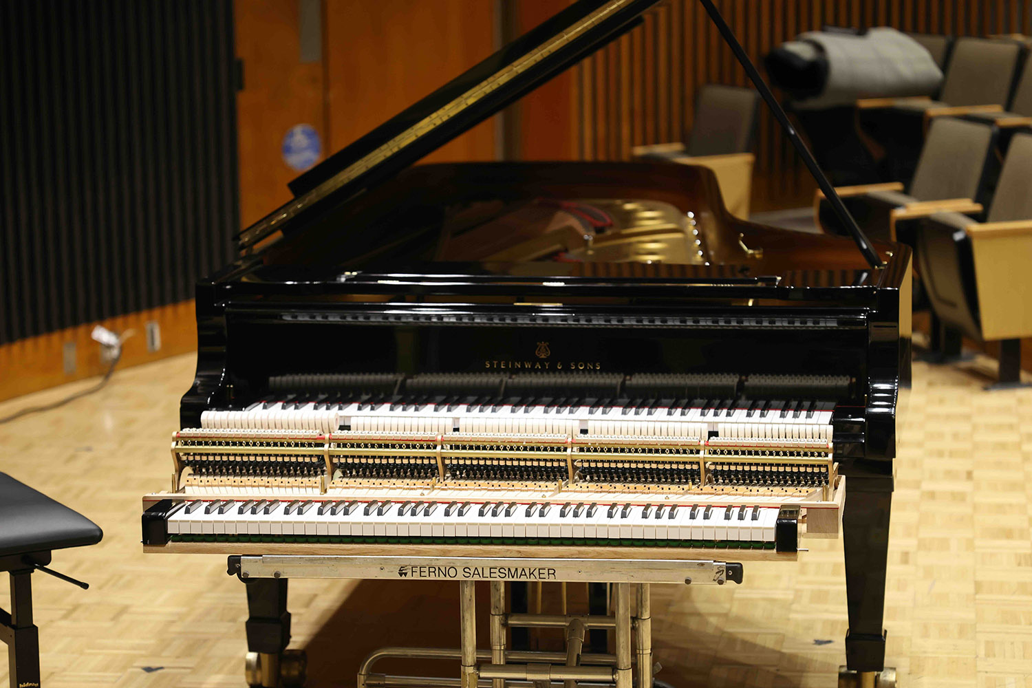 A narrow keyboard is placed before a Steinway grand piano.