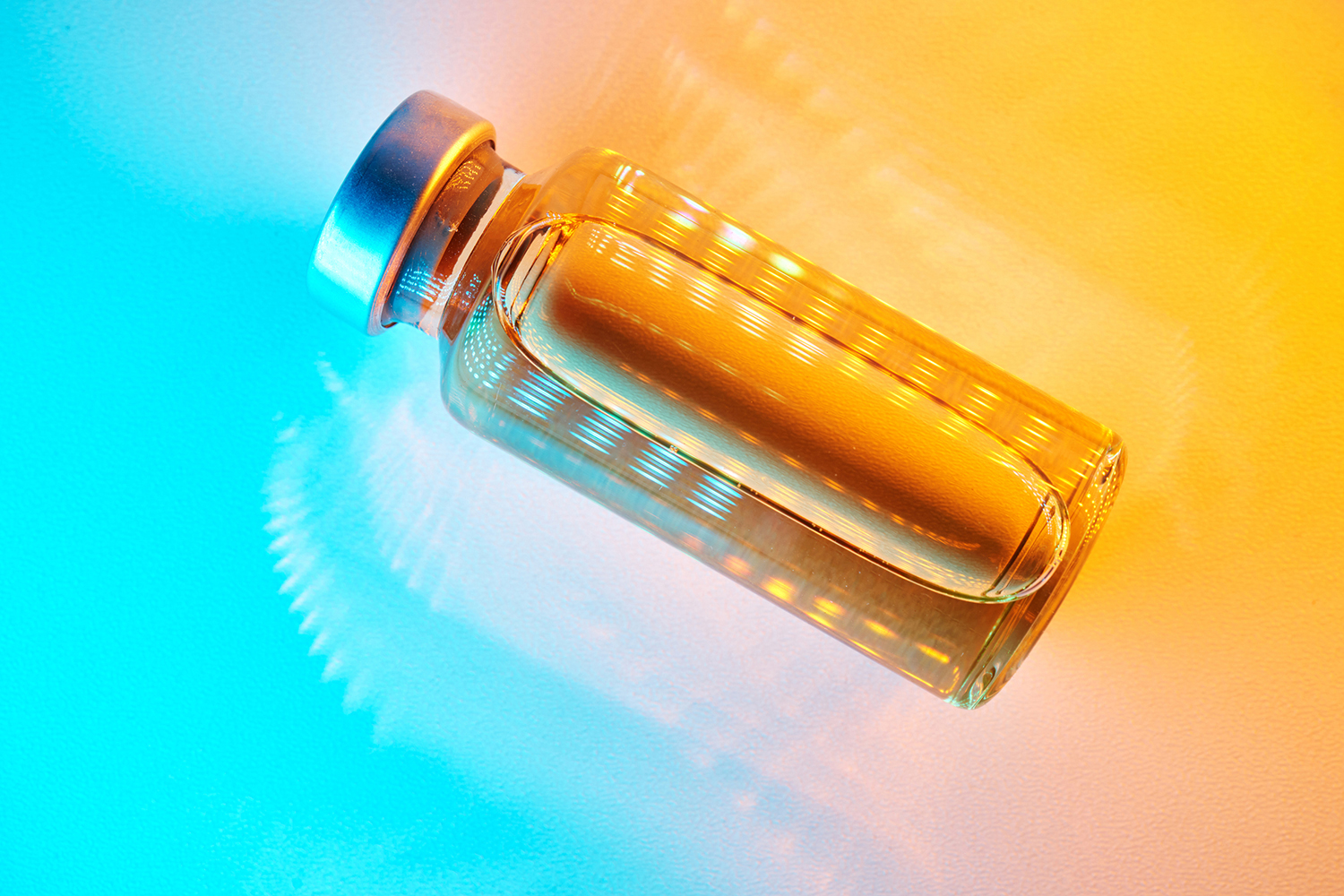 A glass bottle filled with liquid is illuminated with vibrant orange and blue lighting effects.