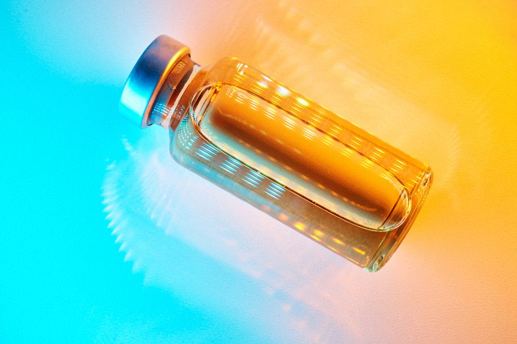 A glass bottle filled with liquid is illuminated with vibrant orange and blue lighting effects.