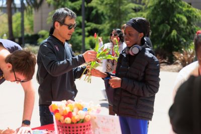 Staff member giving a flower to a student.