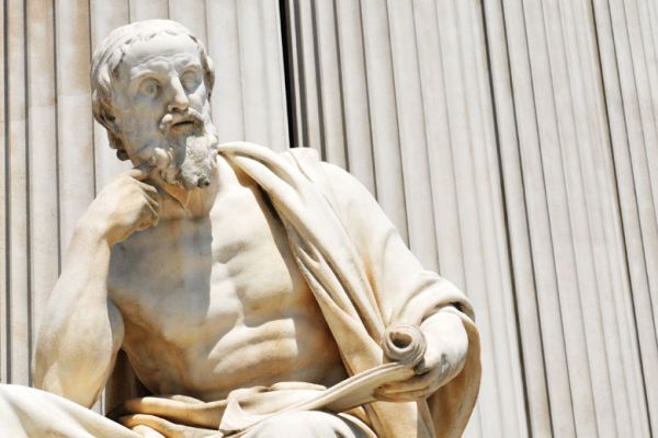 Statue of ancient philosopher holding a scroll. / Photo: Shutterstock