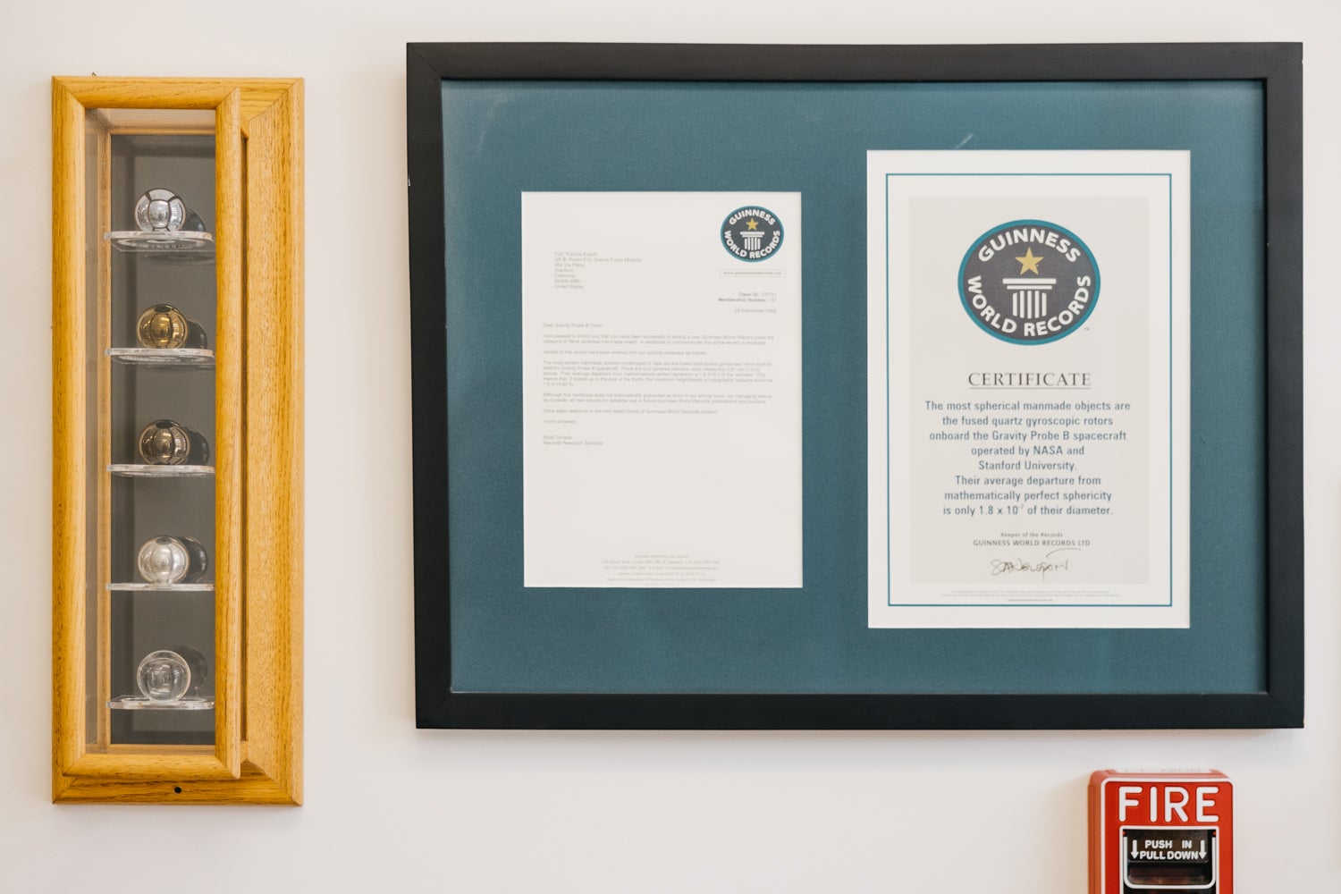 A case with 5 spheres hung next to a letter and certificate from the Guinness World Records