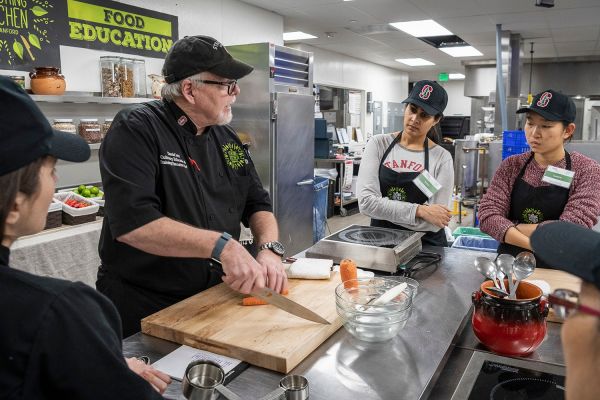 Iott and students stand at a kitchen table.