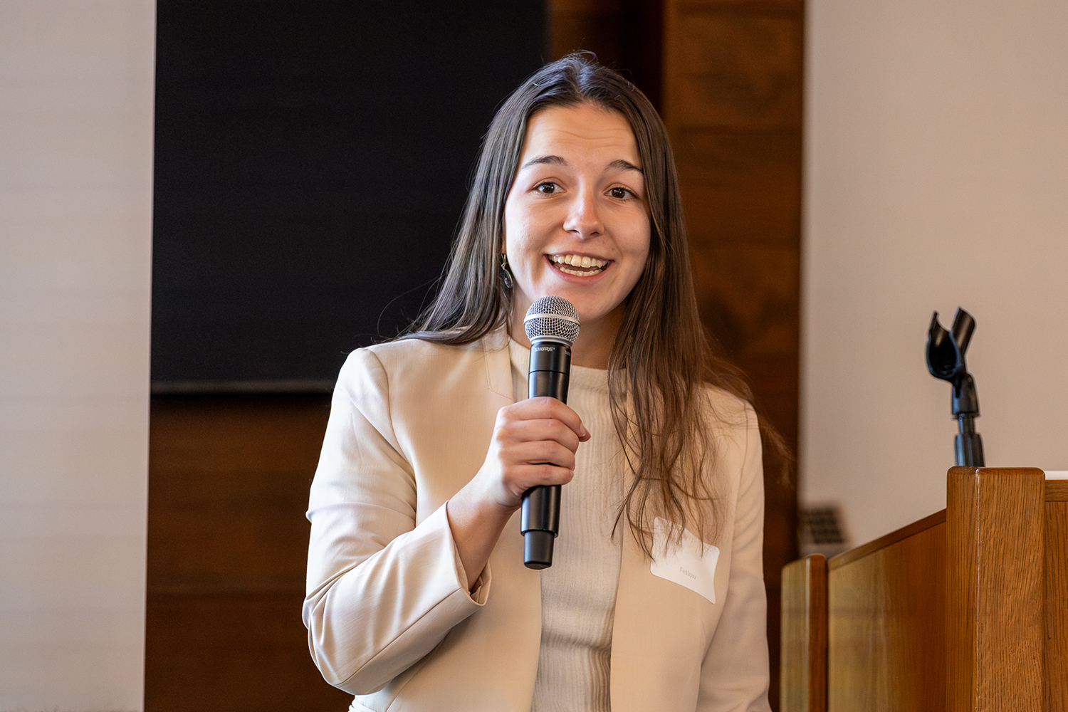 Tami Gjorgjieva holding a mic and giving a talk; she is wearing a beige blazer.