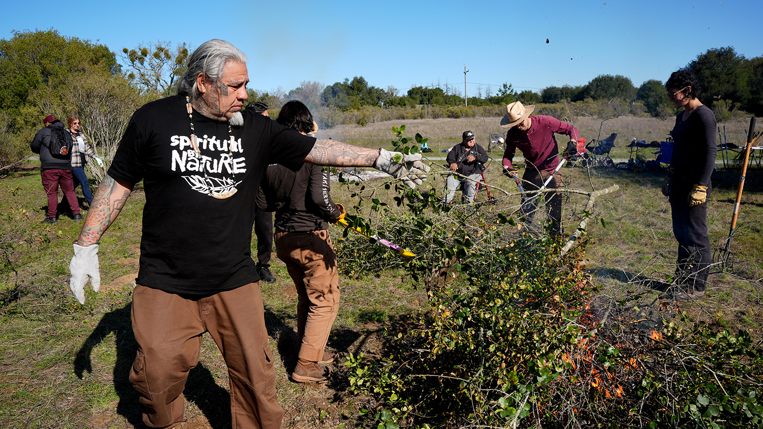 Joey Iyolopixtil Torres adding brush to a fire.