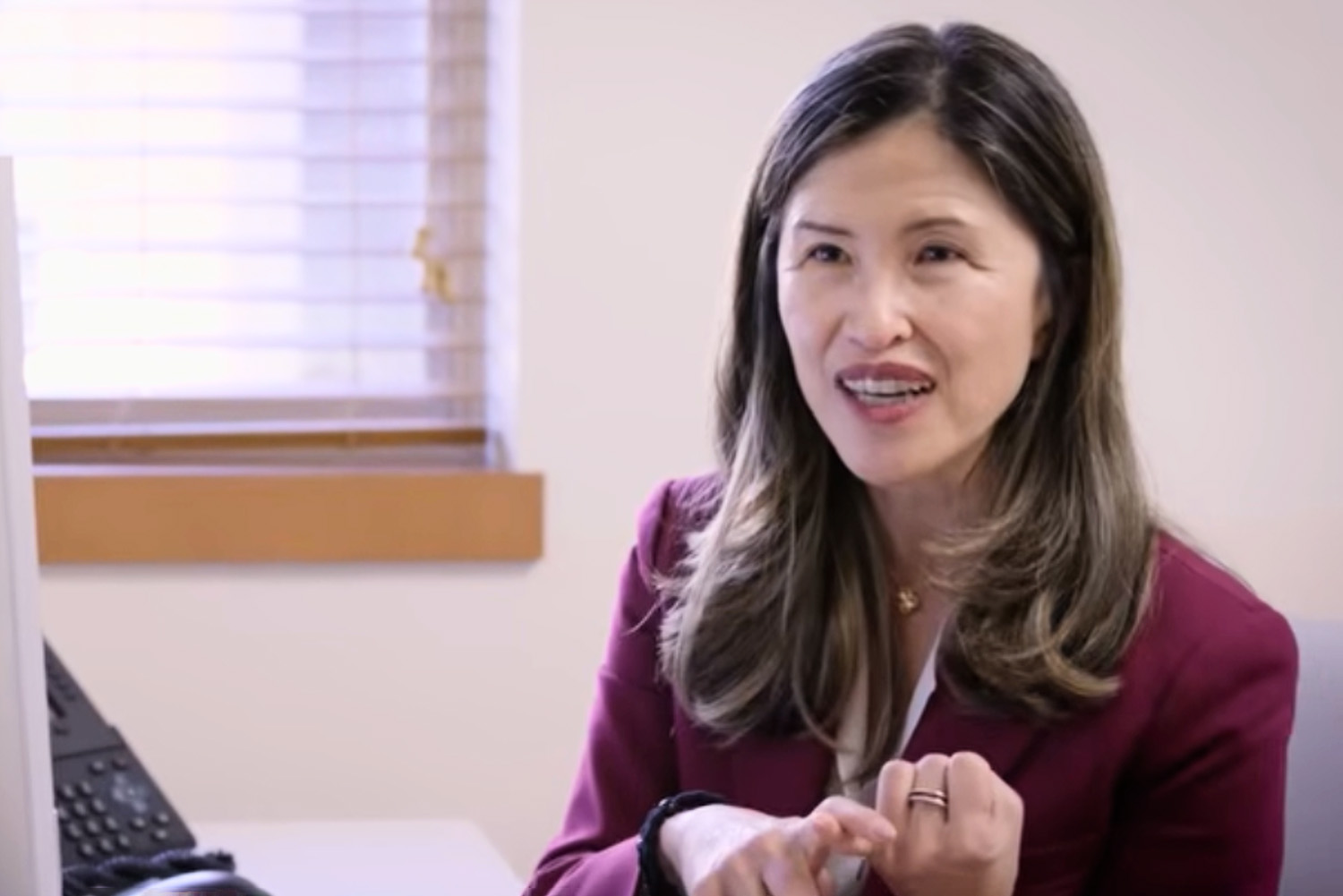 Open video Sun Kim talks with a person across a desk in an office setting. in a modal