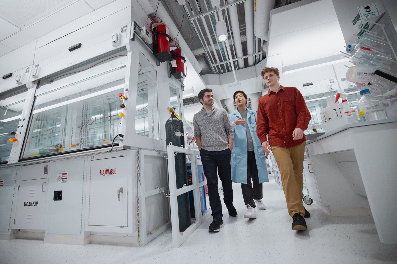 Three people walking together in a lab setting and chatting.