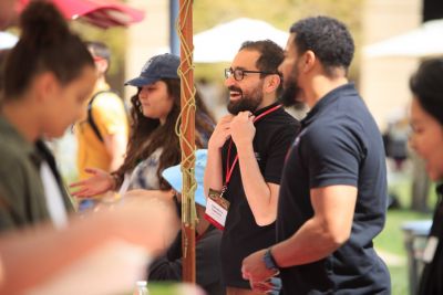 Staff members speaking to students at a table.