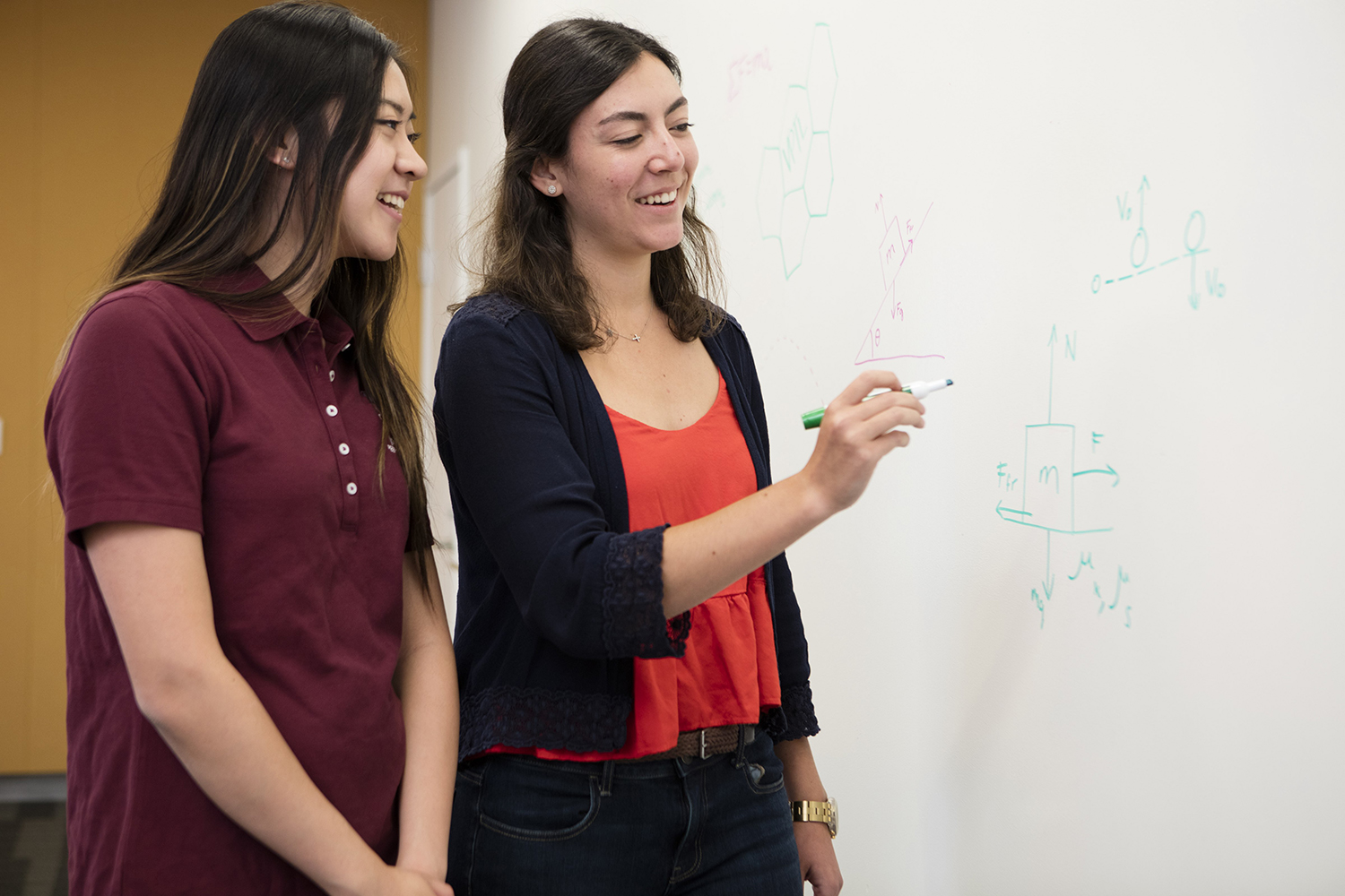 A tutor works on a math problem with a student.