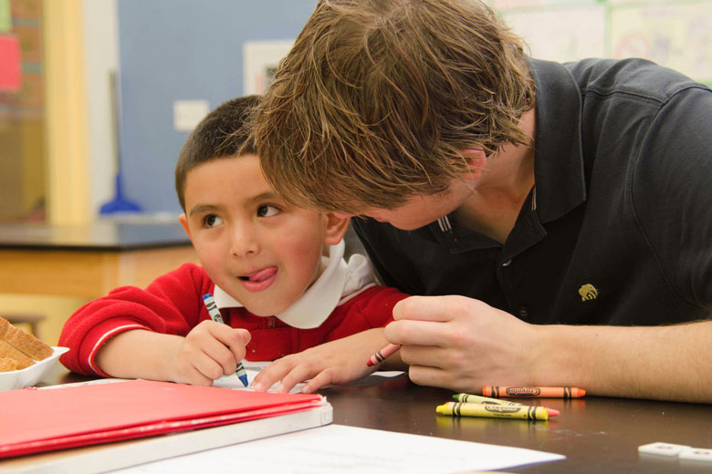 Young man helping a small boy with school work..