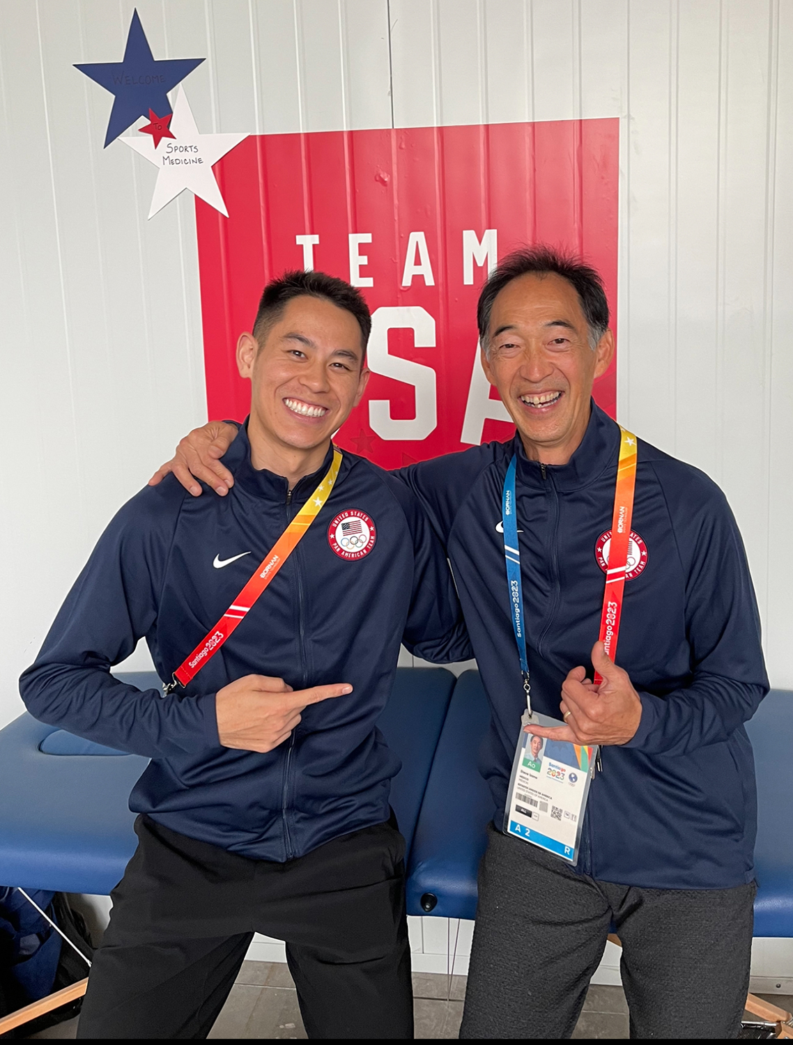 Posing for a photo are Howard Shu, pictured left and is standing and pointing to Dr. Steven Isono who has his arm over Howard's shoulders.