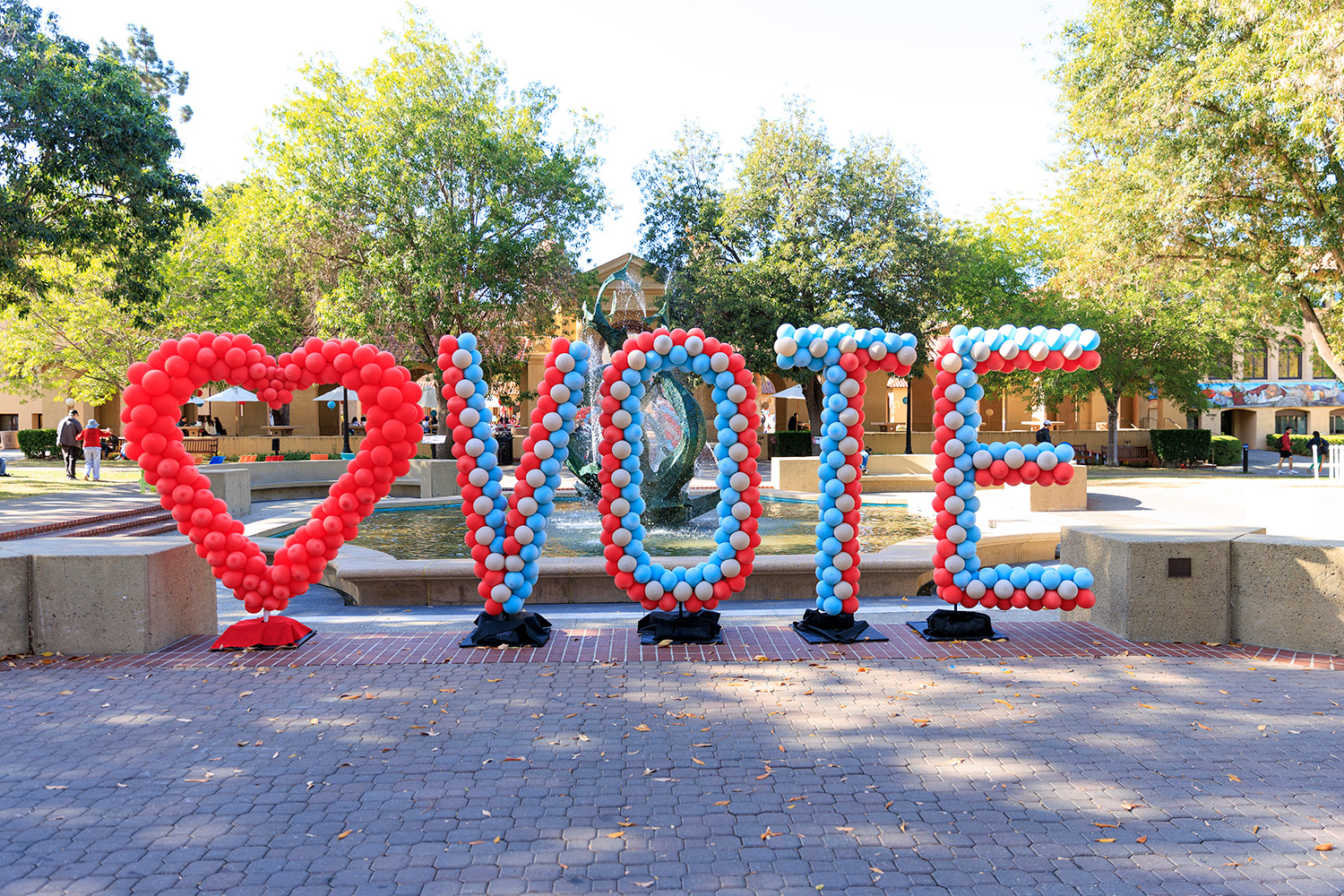 Balloons spell out VOTE in front of White Plaza fountain