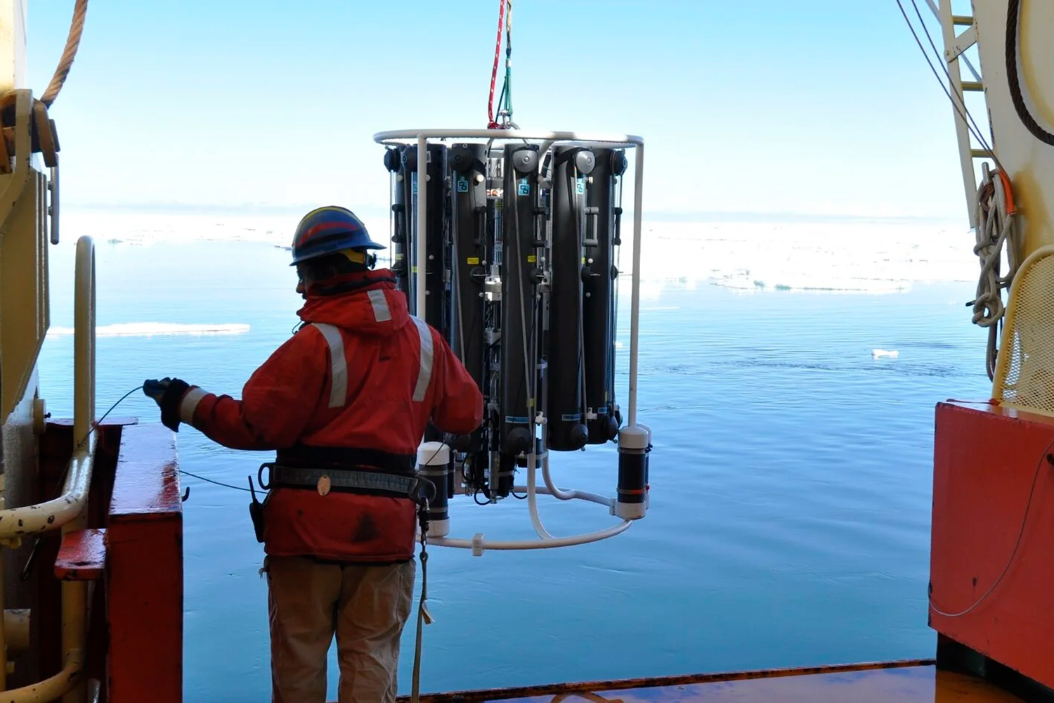 Image of a person on a ship deploying the instrument used to collect water samples from different ocean depths.