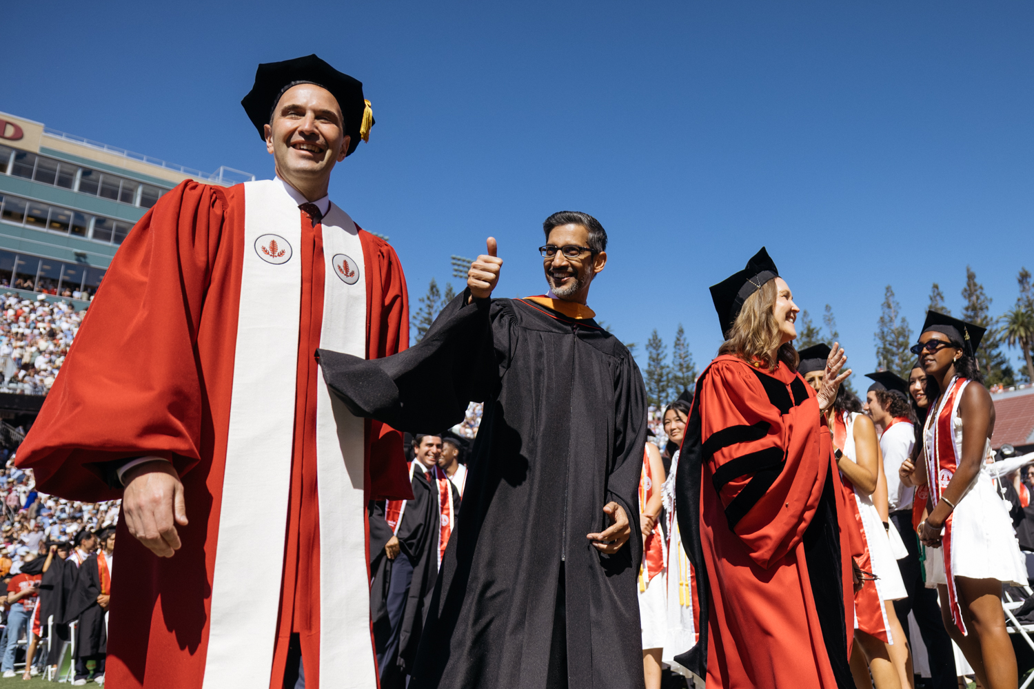 Flanked by President Levin and Provost Martinez, Sundar Pichai in academic regalia gives thumbs-up during during entrance procession.