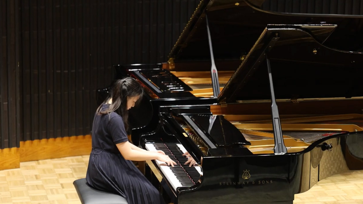 Pianist plays a Steinway piano in a performance space, focused on the keys.
