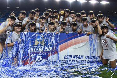 Cardinal women's soccer team with campionship banner