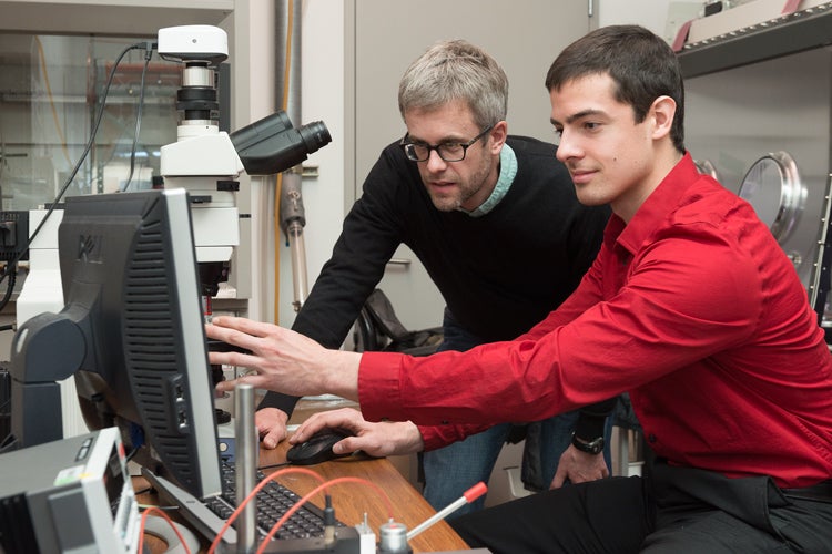 Professor Mike McGehee and graduate student Colin Bailie use a microscope to examine silver nanowires on the solar cell